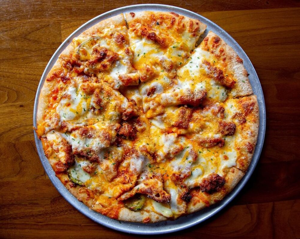 Whole cheesy pizza on plate.