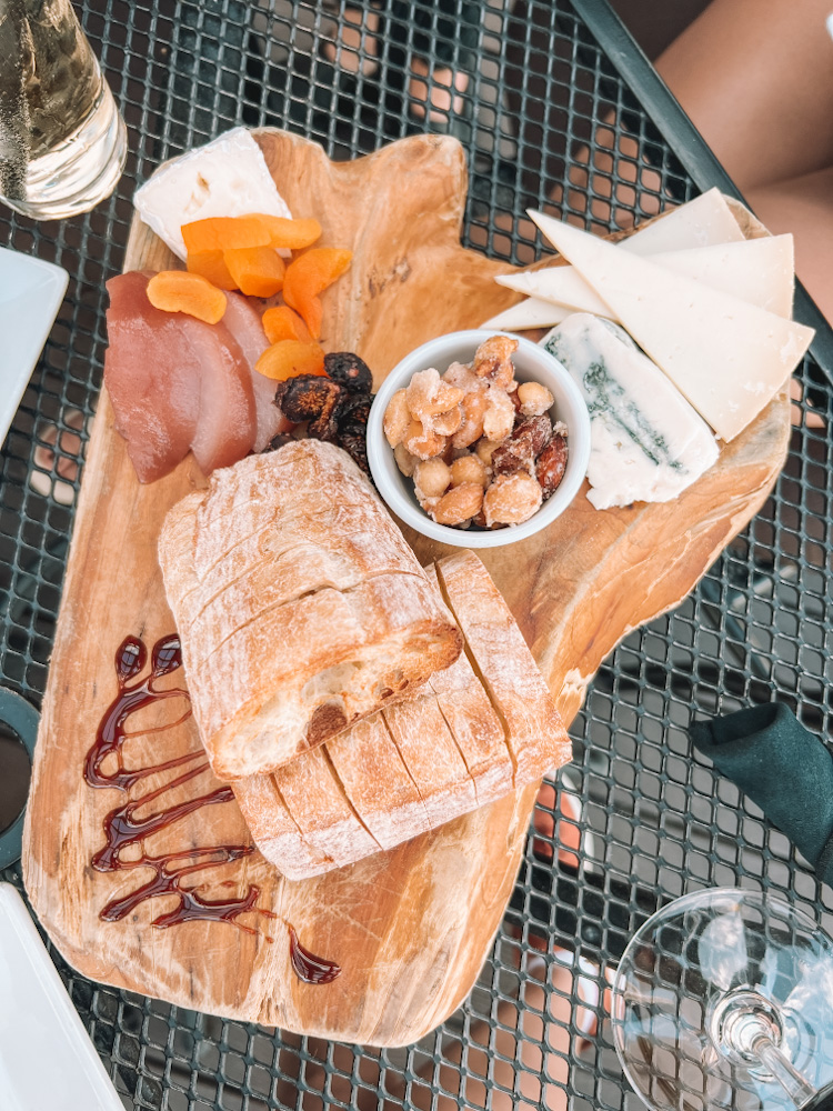 A charcuterie board with bread, meat, cheese, and nuts.